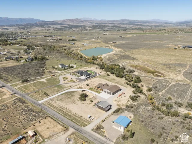 Expansive property featuring a tranquil lake, multiple residential structures, and distant mountain scenery