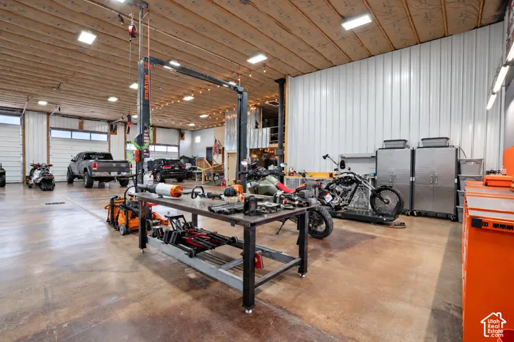 Spacious garage featuring a vehicle lift, multiple garage doors, concrete flooring, and extensive built-in storage cabinetry