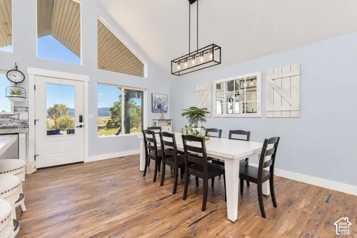 Vaulted ceiling with a contemporary linear chandelier, wood-finish flooring, and multiple large windows