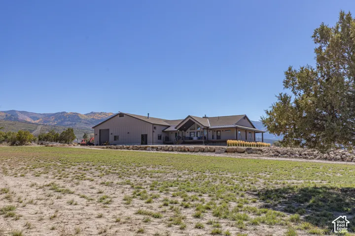Expansive property featuring a metal-sided structure, covered porch, large garage door, and a natural stone retaining wall