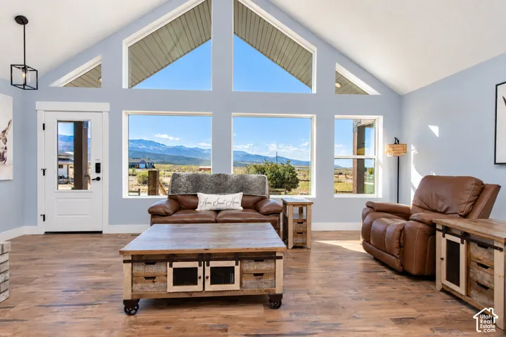 Vaulted ceiling with high windows, wood-finish flooring, white paneled door with glass insert, black exterior light fixture, and light blue wall paint