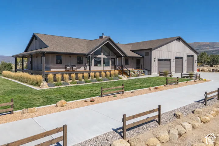 Modern farmhouse exterior with board and batten siding, expansive front porch, three-car garage, concrete driveway, and manicured landscaping