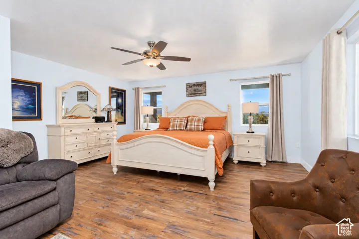 Room with wood-finish flooring, a ceiling fan with integrated lighting, and multiple windows