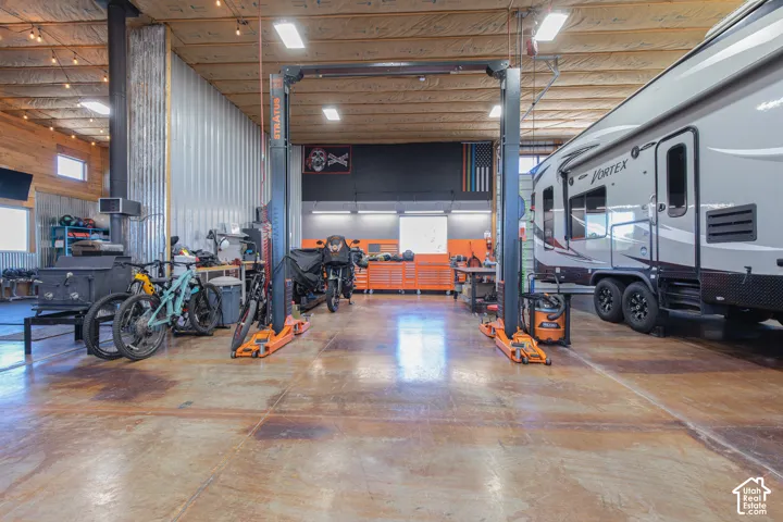 Spacious garage with high ceilings, exposed wood beams, concrete flooring, and metal paneling