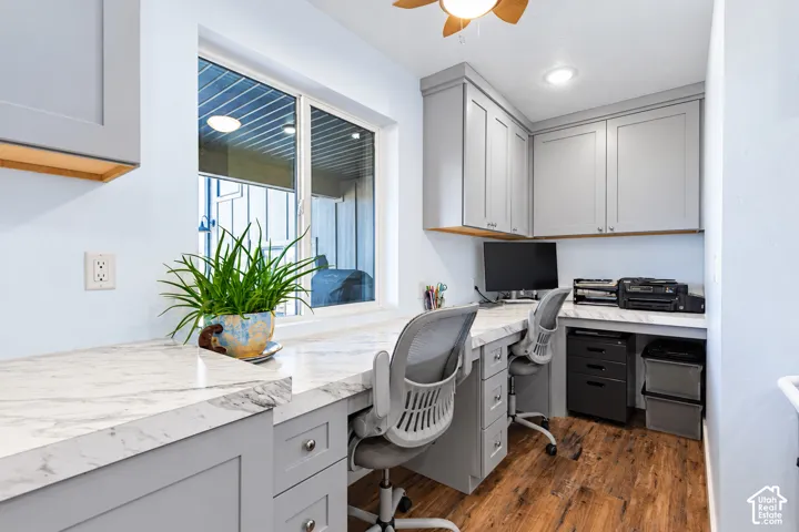 Built-in desk with extensive counter space, custom cabinetry, wood-finish flooring, and a large window