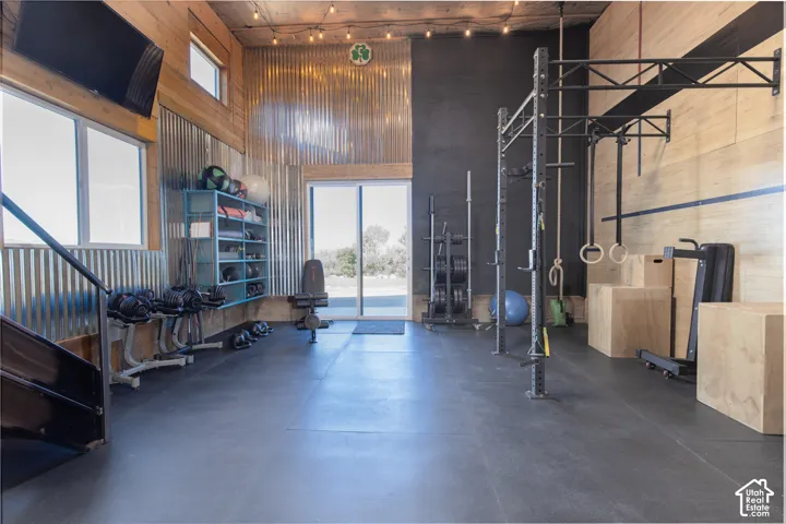 Dedicated fitness area featuring rubber flooring, corrugated metal wall accents, wood-paneled walls, and a sliding glass door