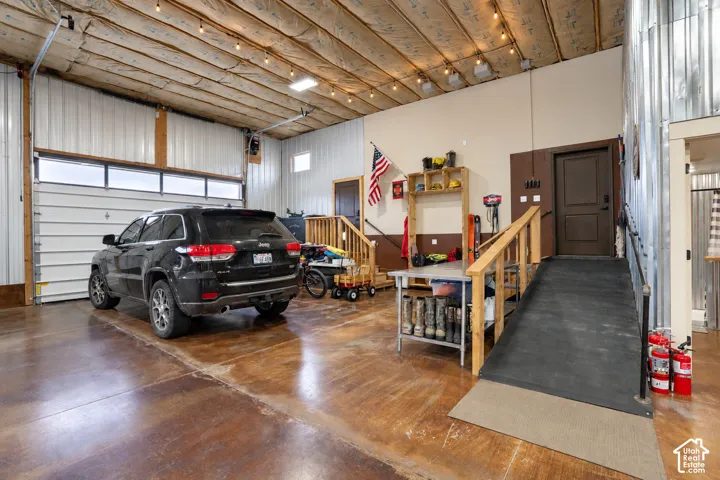 Polished concrete flooring, steel panel walls, a large overhead garage door with upper windows, and a built-in ramp with wooden handrails