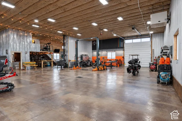 Spacious utility building featuring a polished concrete floor, corrugated metal walls, and a wood plank ceiling