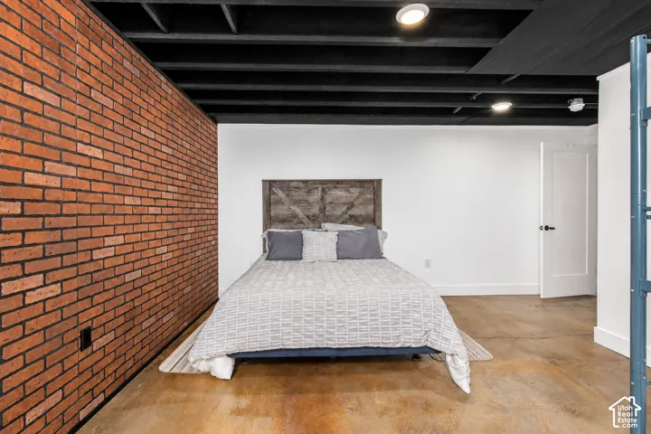 Exposed brick accent wall, white painted walls, black painted ceiling with exposed beams, recessed lighting, and a solid core interior door