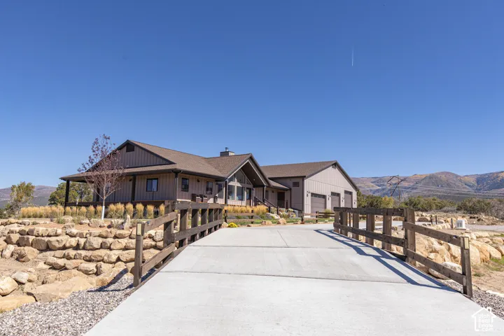 Exterior featuring a covered front porch, attached multi-car garage, concrete driveway, and natural rock landscaping