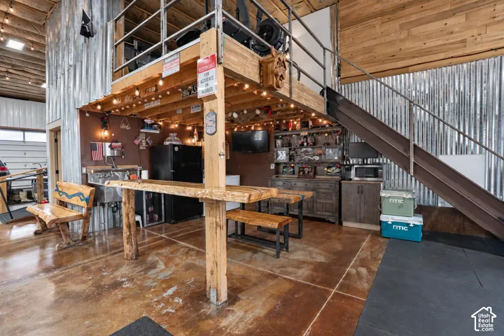 Polished concrete flooring, exposed wood beam ceiling, corrugated metal wall paneling, and an exposed metal staircase