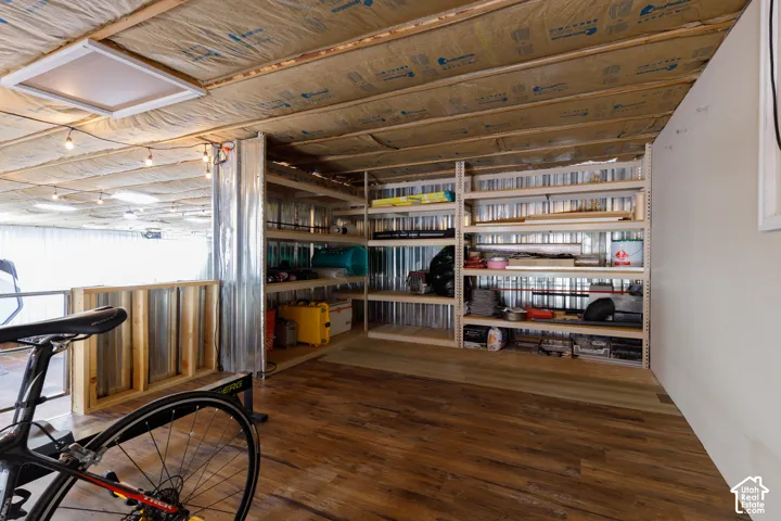 Wood-finish flooring, exposed ceiling insulation, recessed lighting, and extensive built-in shelving