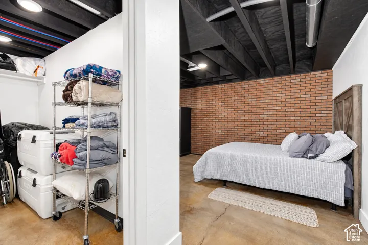 Exposed brick accent wall, finished concrete flooring, painted exposed ceiling beams, and recessed lighting