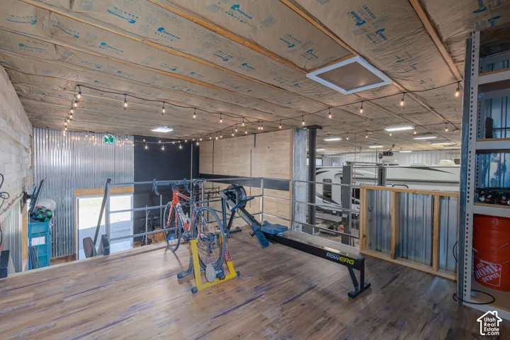 Loft space featuring wood-finish flooring, string lighting, and corrugated metal wall accents