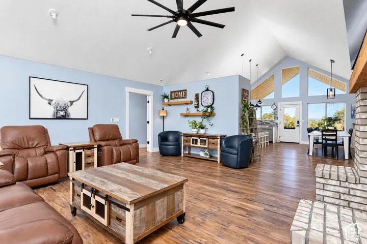 Vaulted ceiling with exposed wood-finish beams, wood-finish flooring, brick-finish fireplace, and multi-pane windows