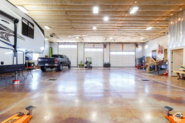 Spacious garage featuring three overhead doors, polished concrete flooring, and ample overhead lighting