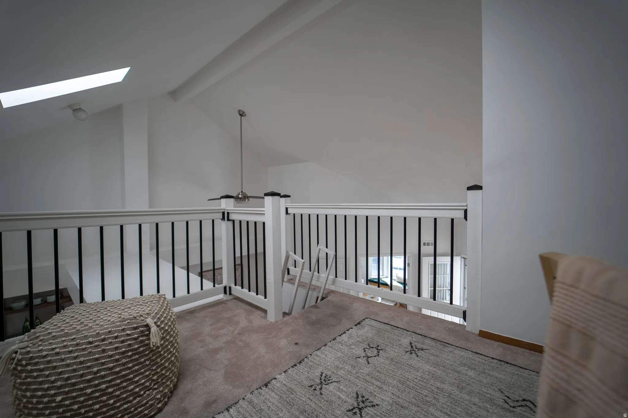 Hallway with carpet floors, beamed ceiling, and a skylight