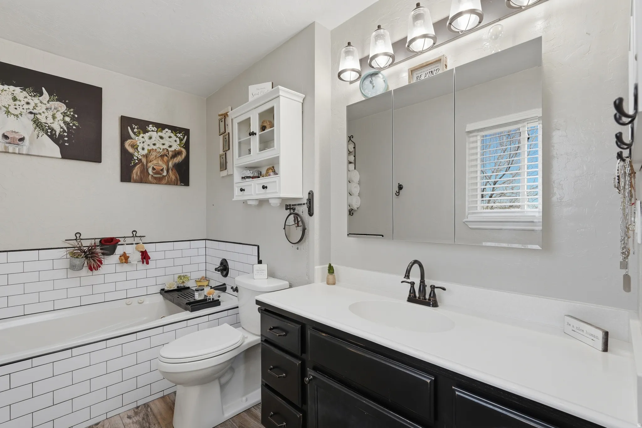 Full bath with a bath, vanity, and dark wood-style floors