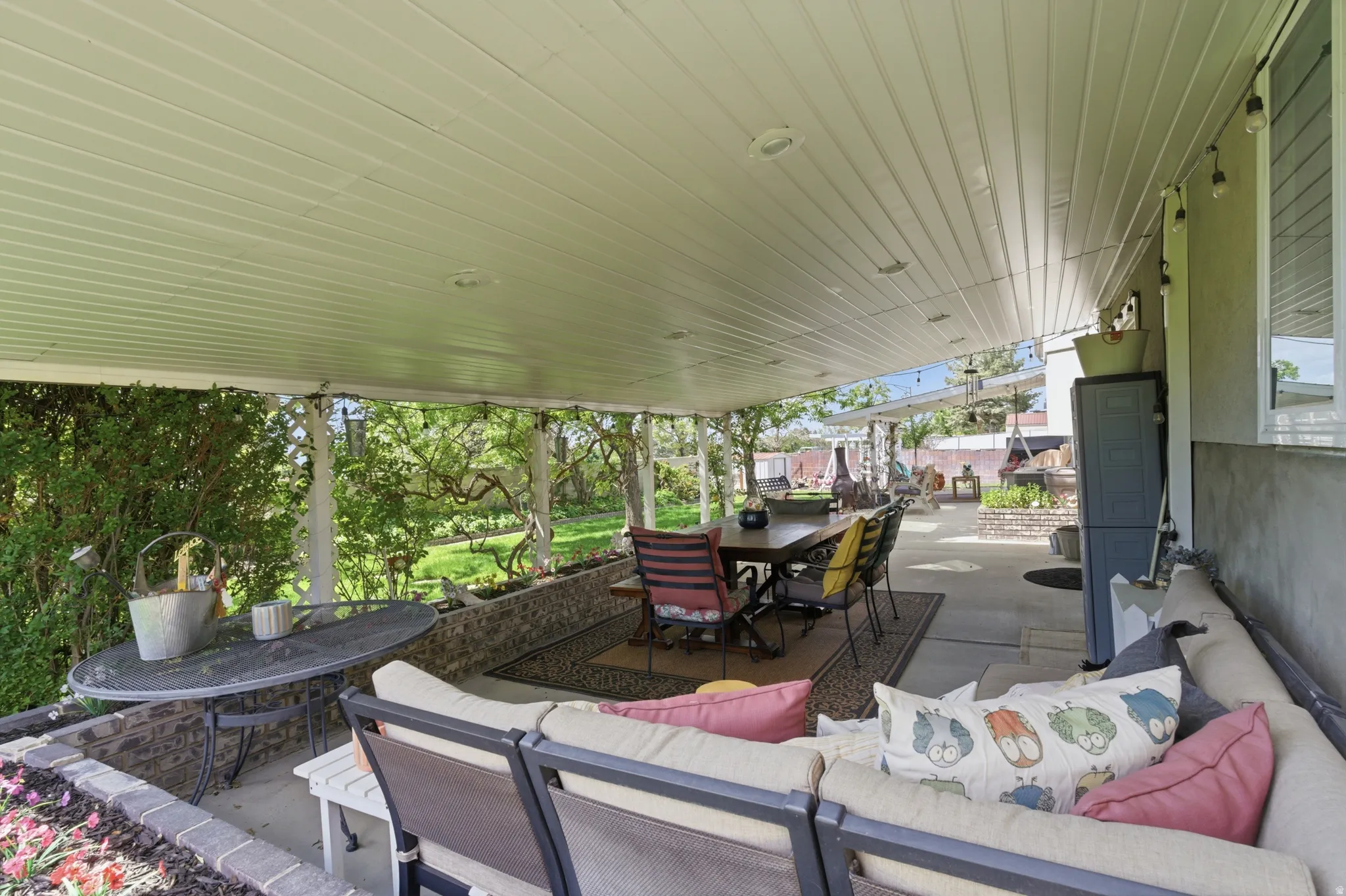 Expansive covered patio featuring a slatted ceiling, recessed lighting, string lighting, and an outdoor dining area