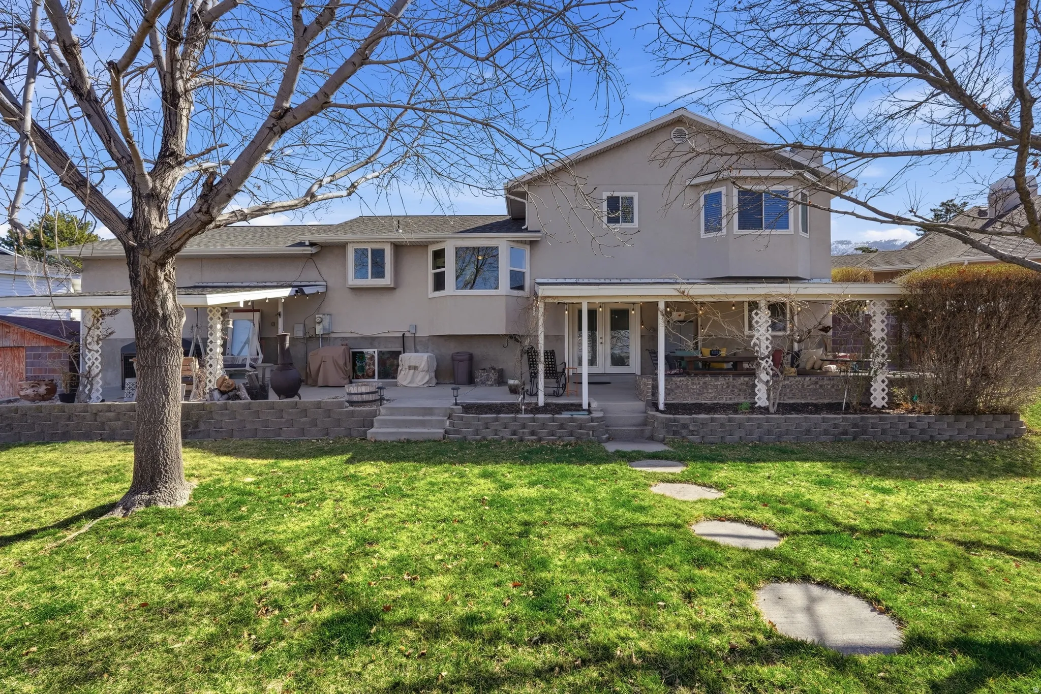 Rear view of house featuring stucco siding, a patio area, and a lawn