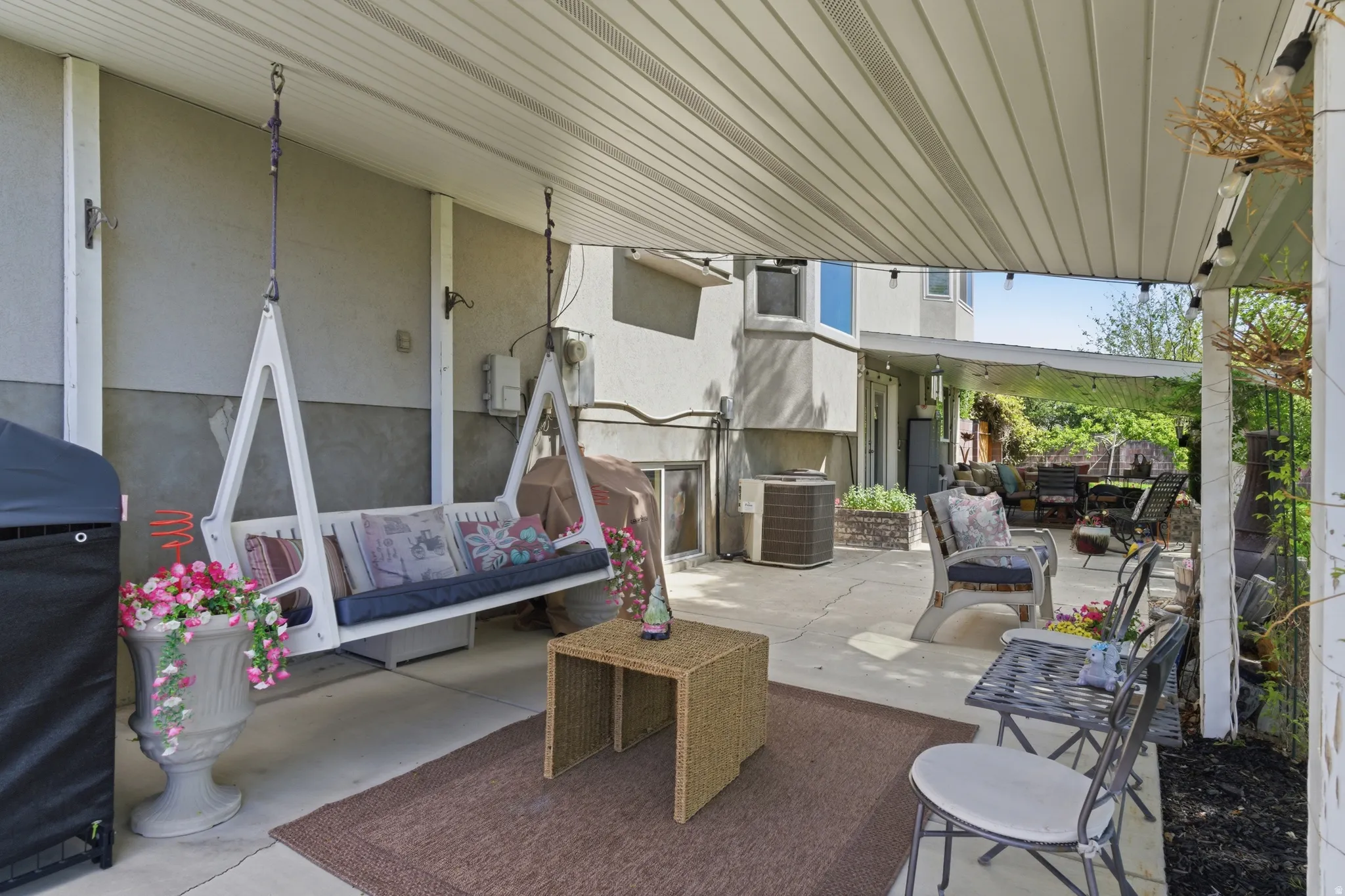 Covered patio featuring an outdoor swing and string lighting