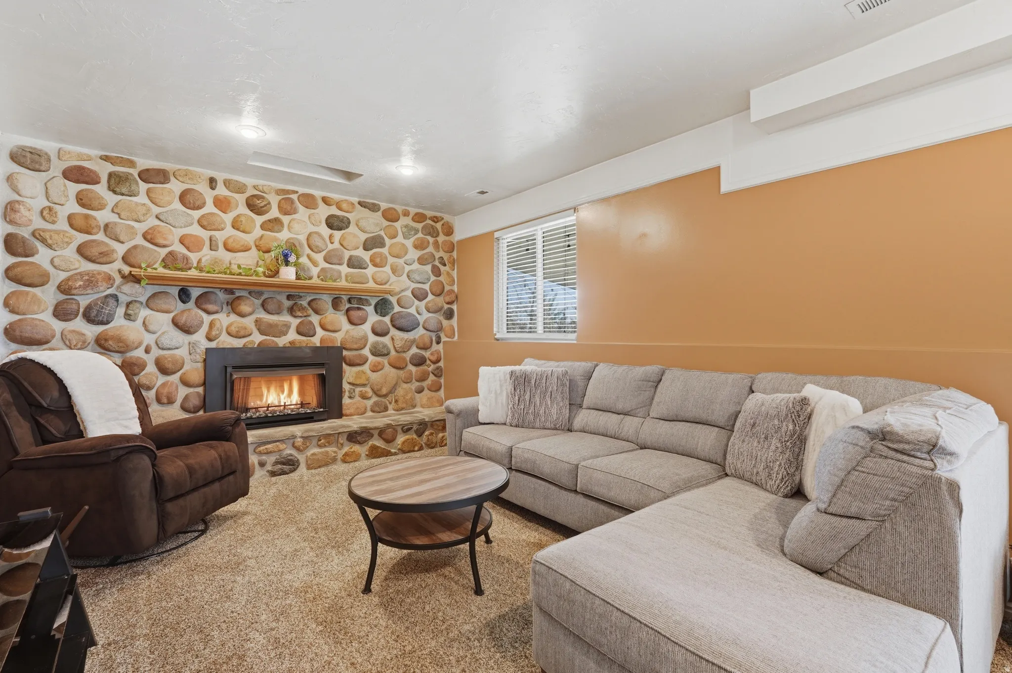 Living room featuring a stone fireplace and carpet flooring