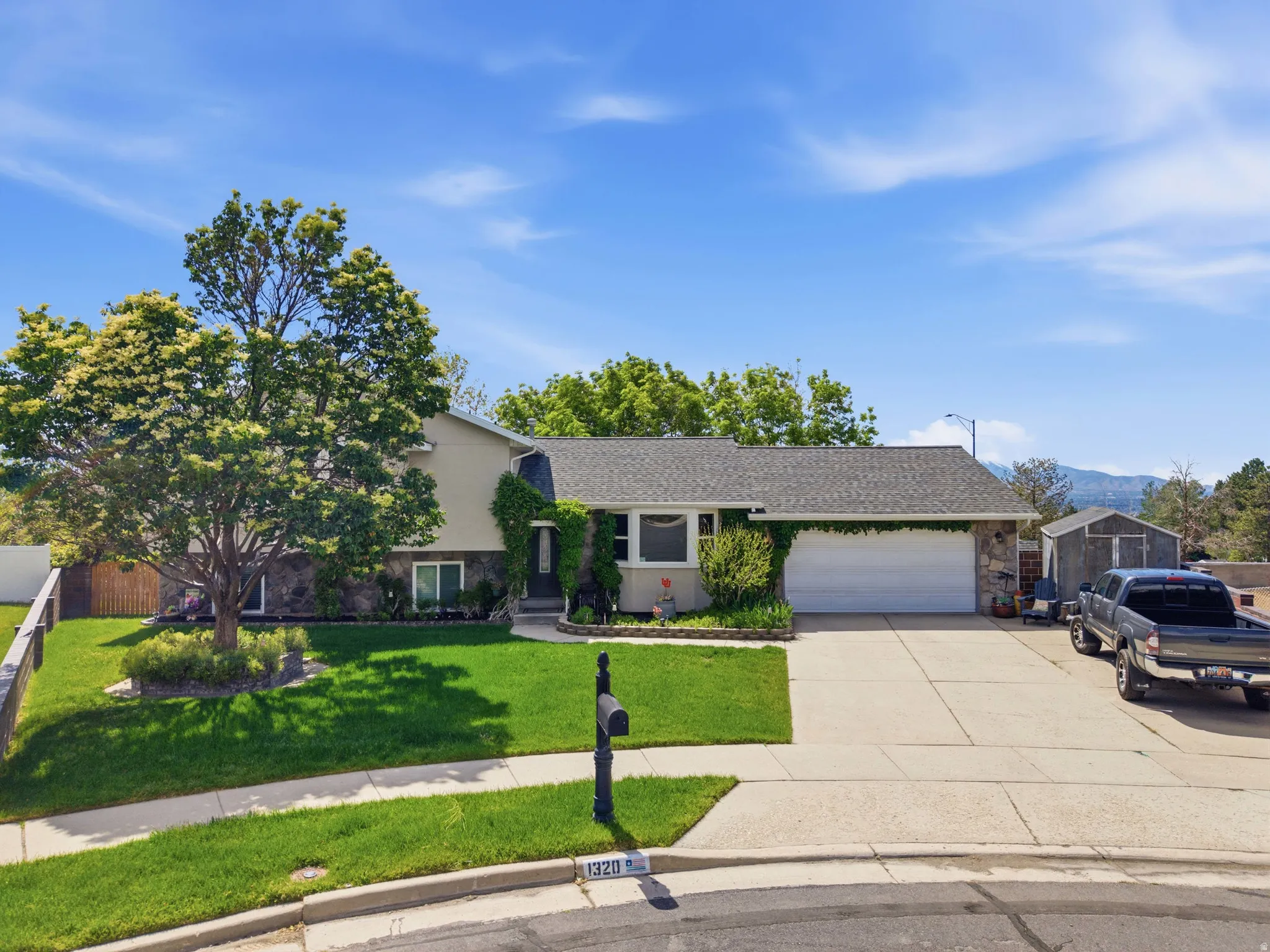 Single-story residence featuring a two-car garage, stone and stucco exterior, and a gabled roofline