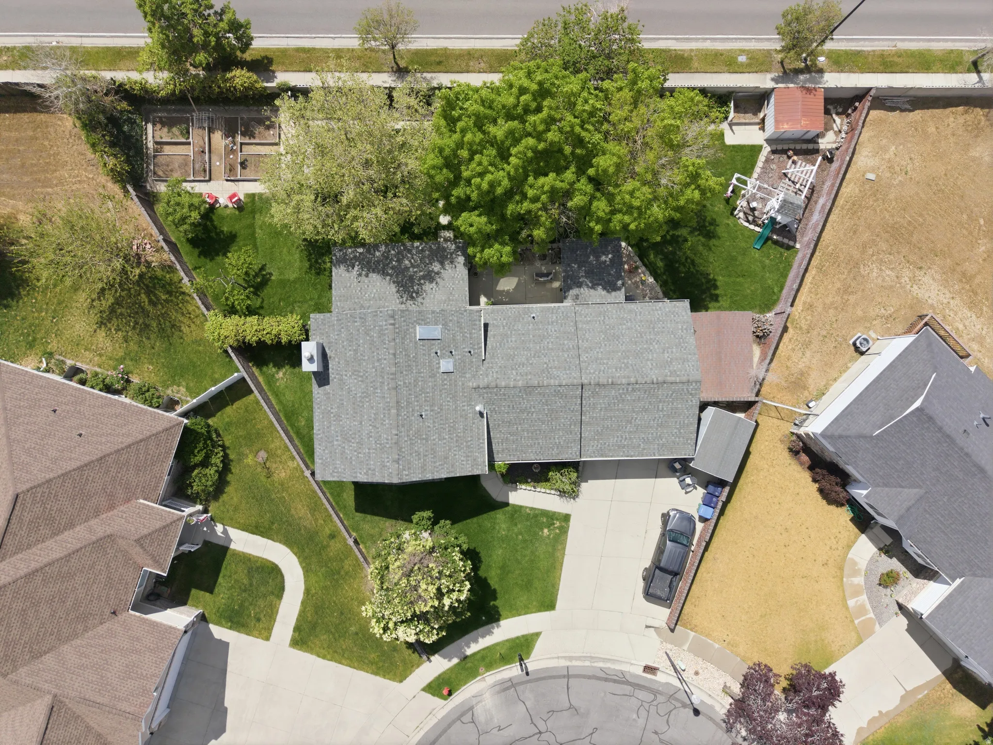 Aerial perspective showcasing a property with a grey shingle roof and a concrete driveway