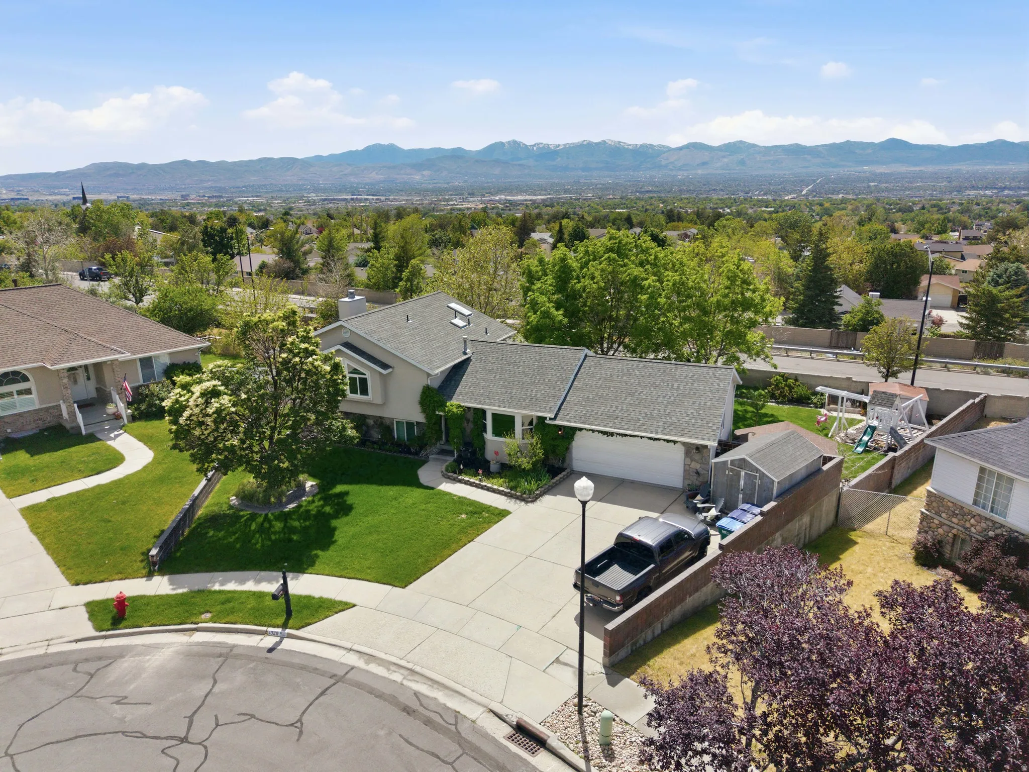 Two-story residence featuring a gray shingle roof, attached garage, and stone facade accents