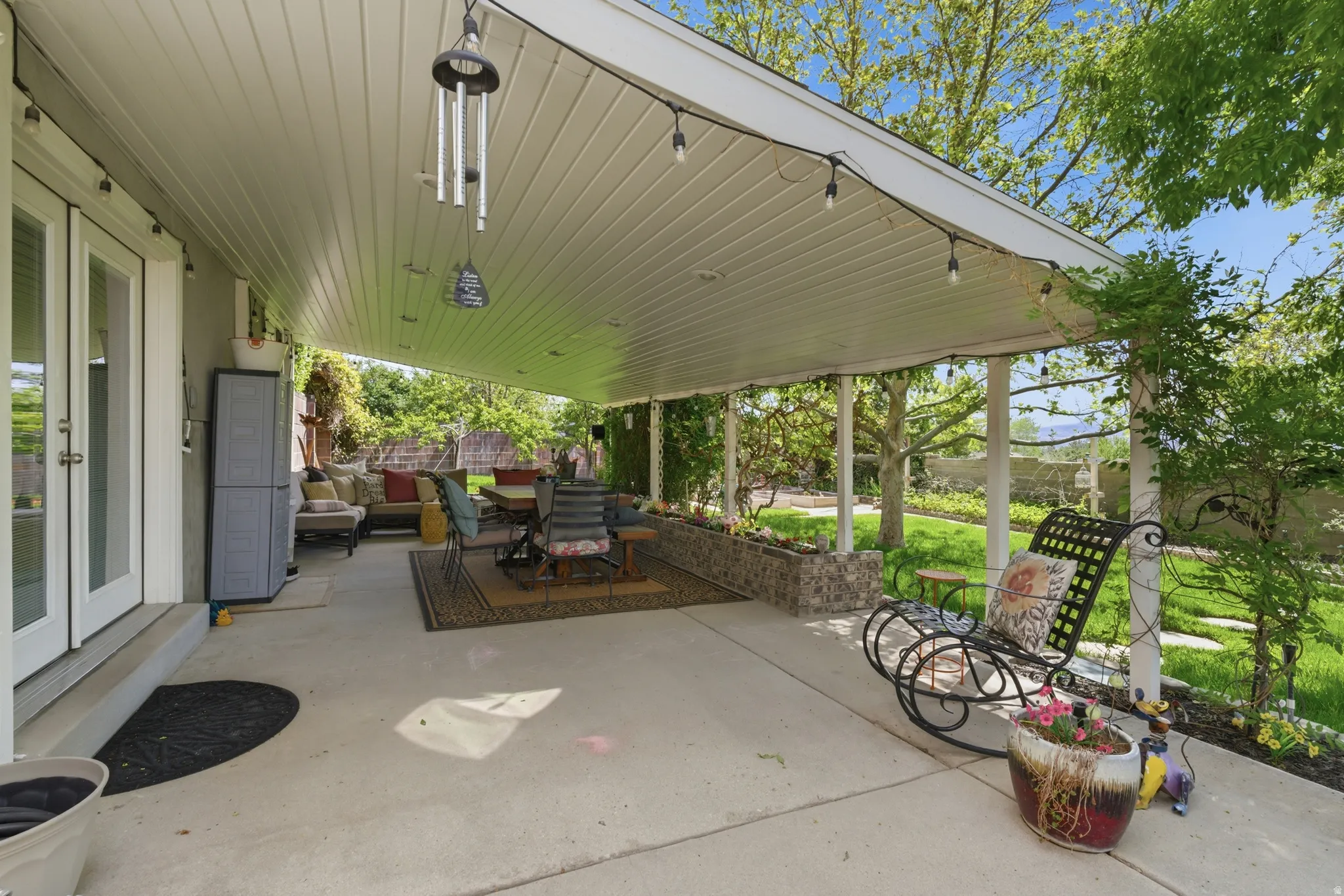 Expansive covered patio featuring a concrete surface, white tongue-and-groove ceiling, and string lighting