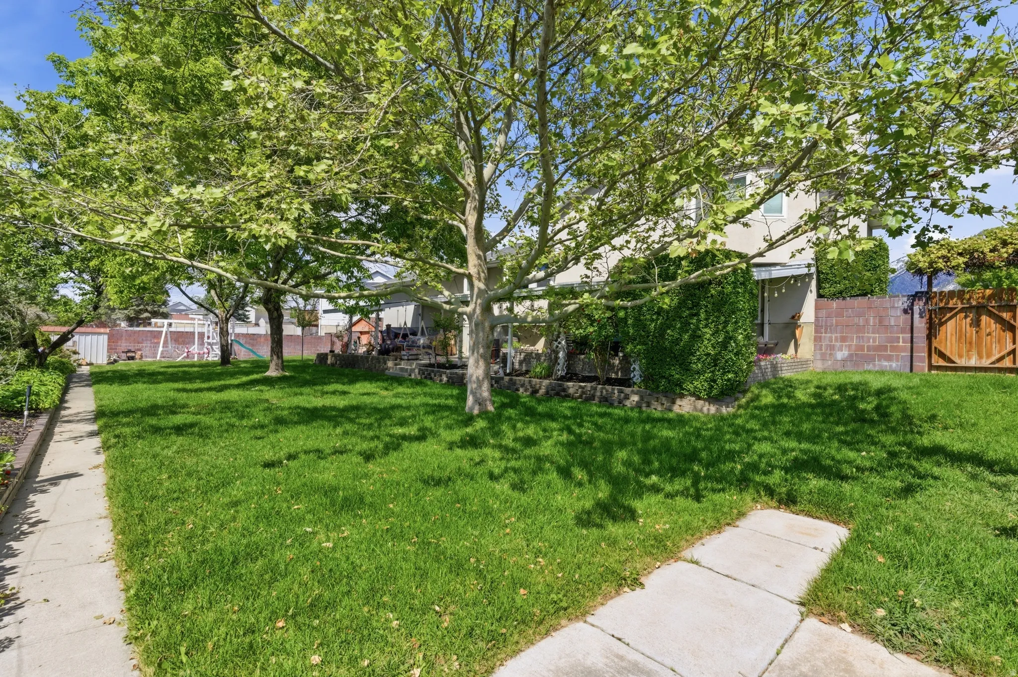 Expansive green lawn with mature trees providing natural shade