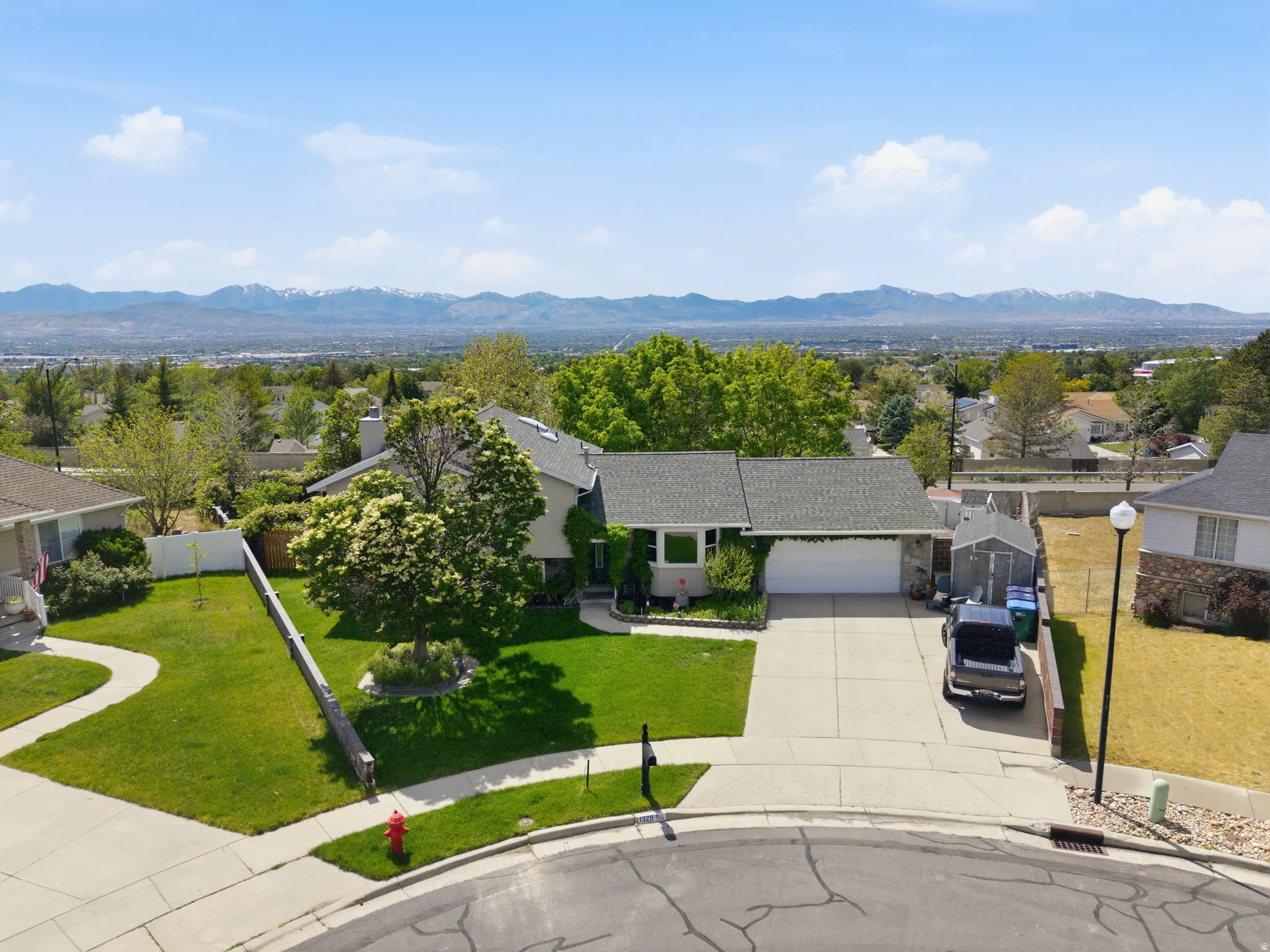 Contemporary ranch-style residence featuring a prominent two-car garage, established front yard landscaping, and a paved driveway