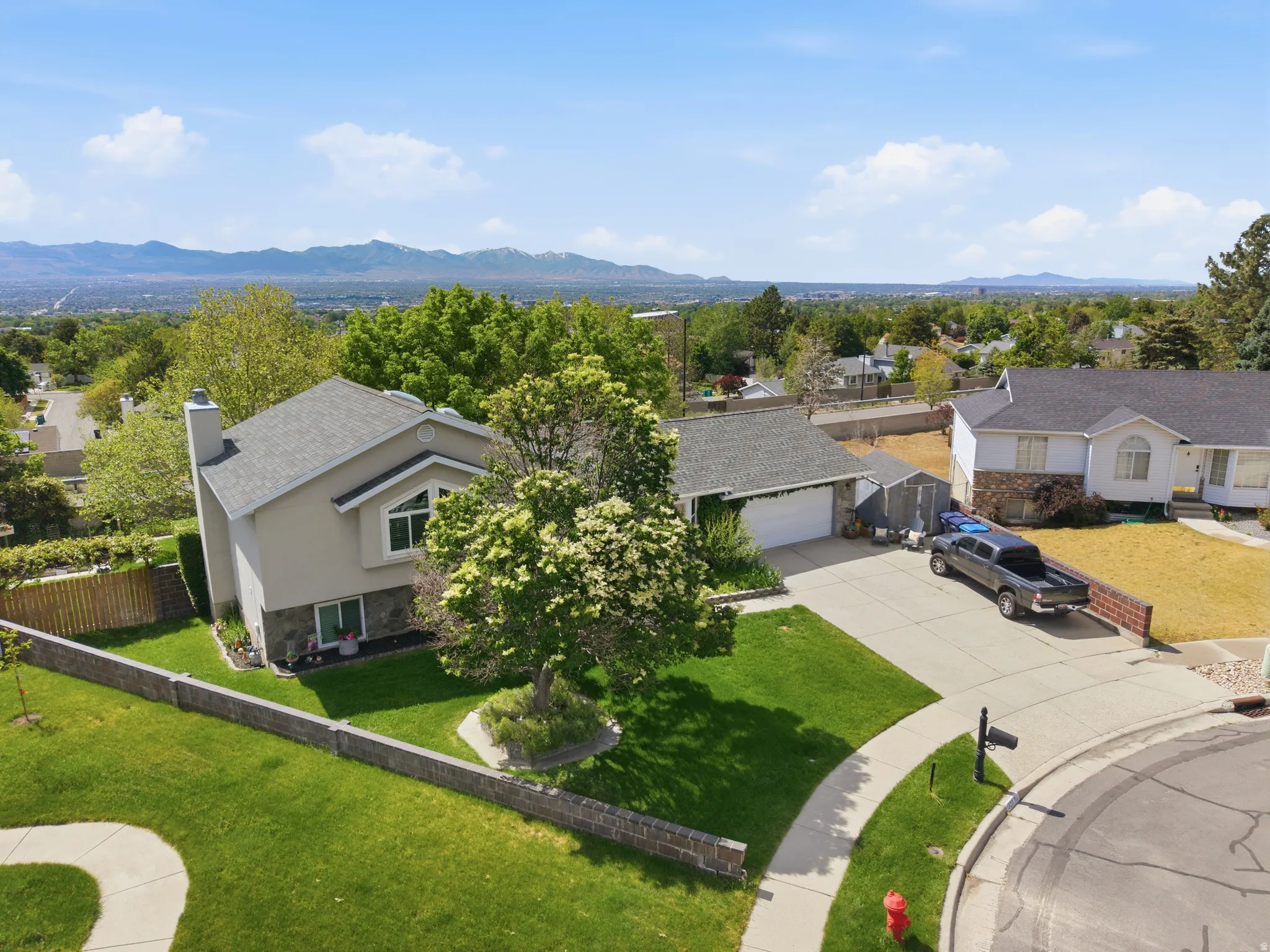 Exterior residence featuring stucco and stone-finish siding, an attached garage, and a concrete driveway