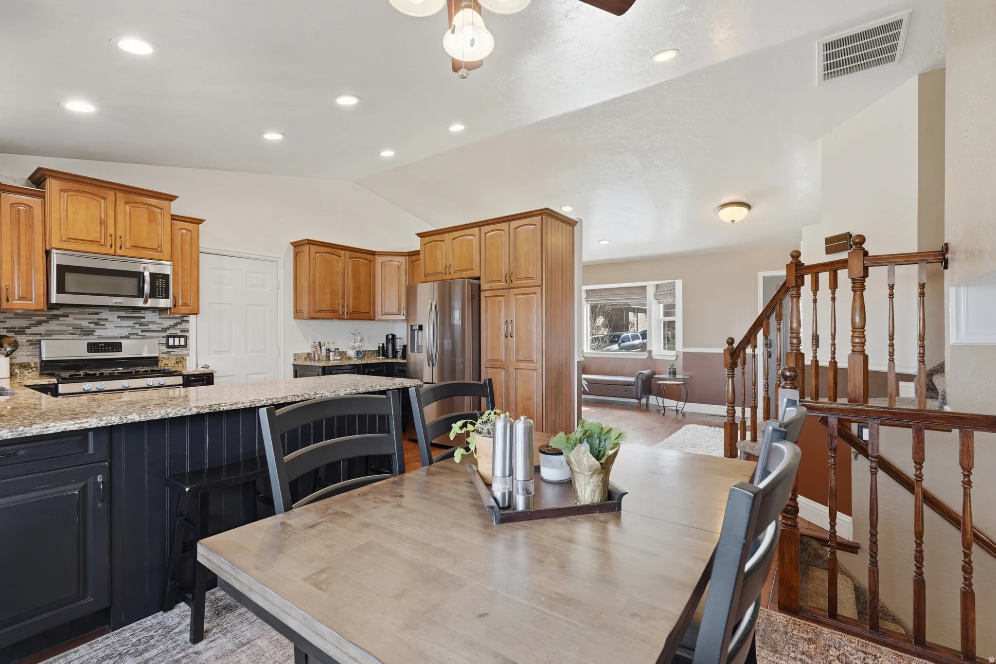 Kitchen with light stone counters, stainless steel appliances, vaulted ceiling, tasteful backsplash, and a ceiling fan