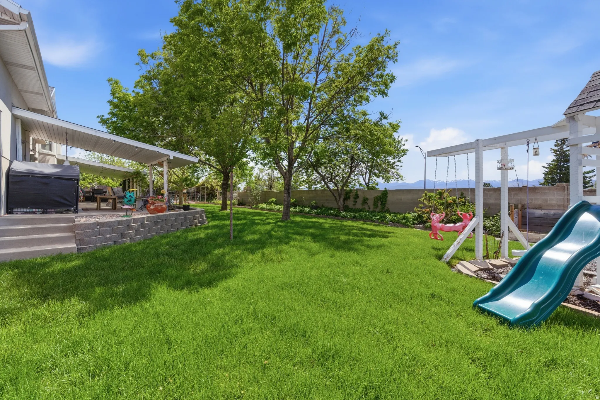 Expansive green lawn with mature trees and a concrete block retaining wall