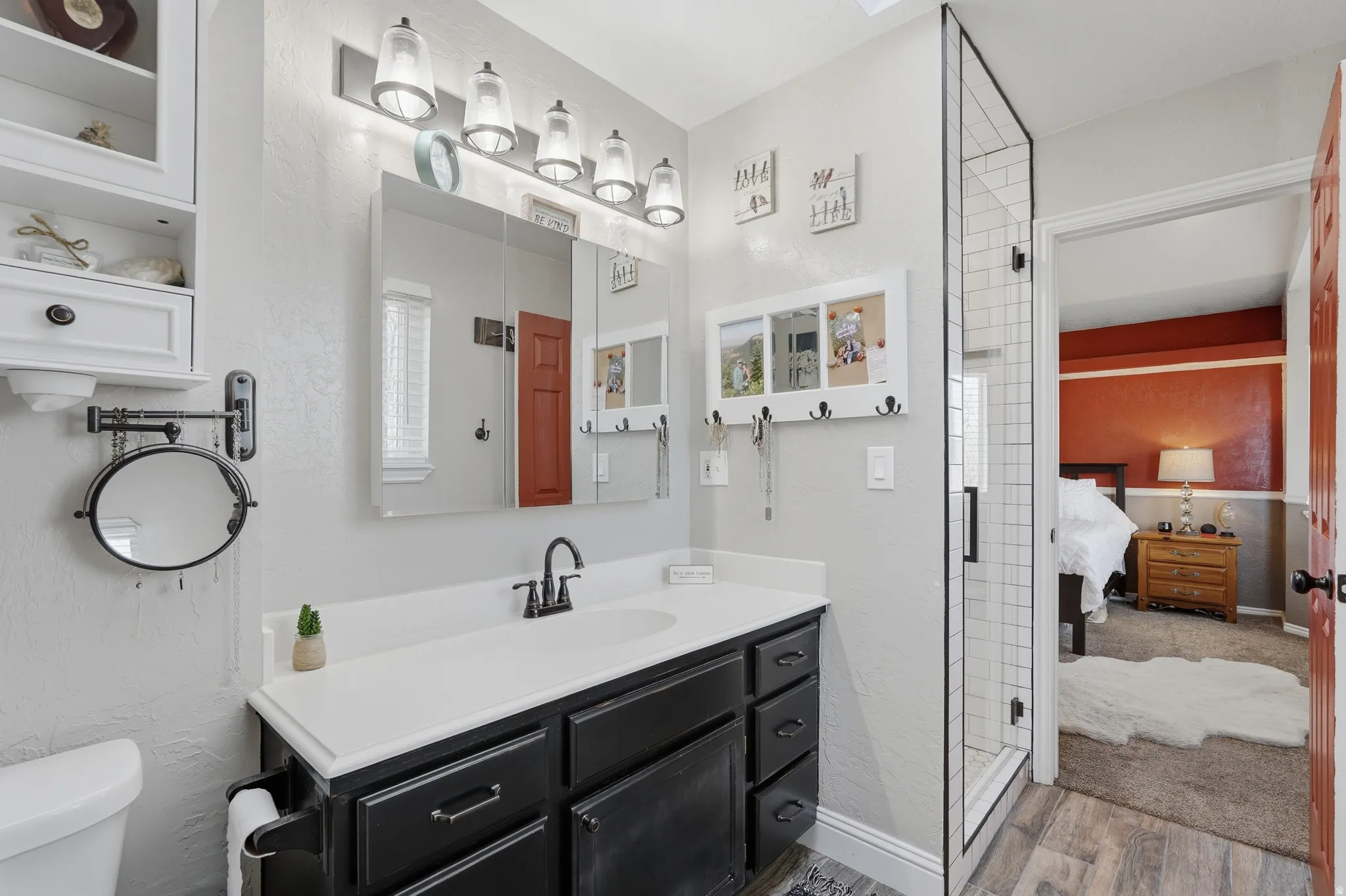 Full bathroom with ensuite bathroom, a stall shower, vanity, light wood-type flooring, and a textured wall