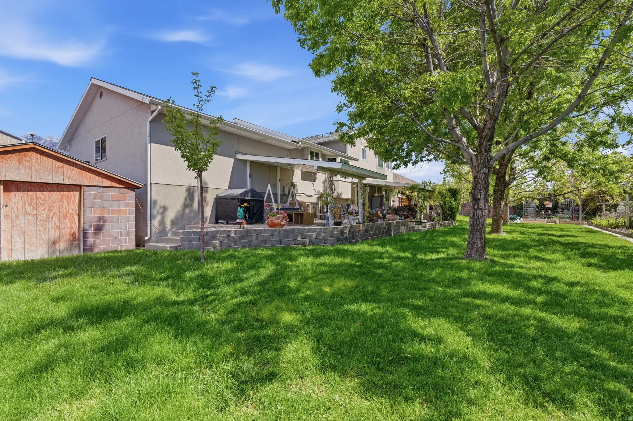Expansive lawn with mature trees and a multi-level patio