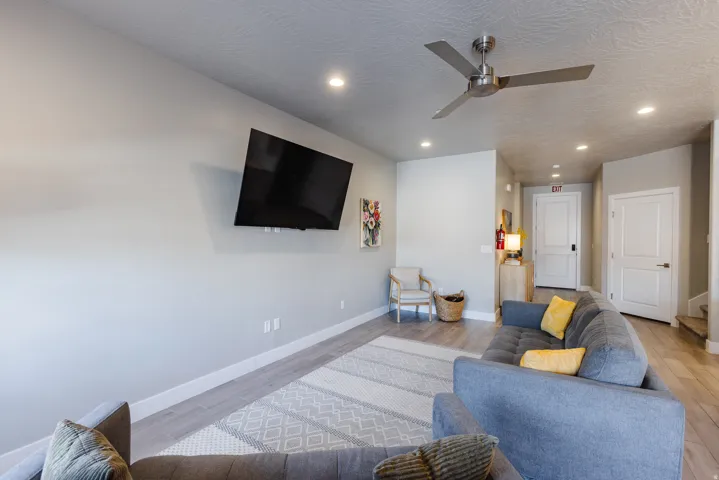 Living room featuring light wood-style floors, ceiling fan, recessed lighting, and a textured ceiling