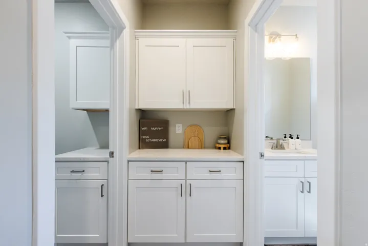 Bar with white cabinets and light stone countertops