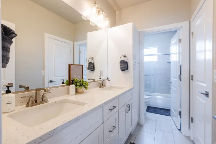 Full bath with double vanity and bath / shower combo with glass door