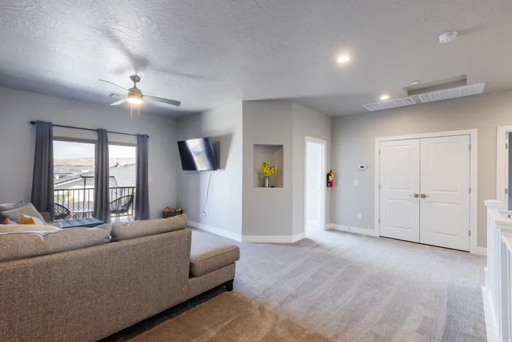 Carpeted living area featuring ceiling fan and a textured ceiling