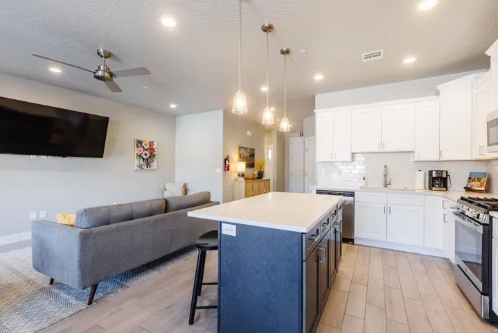 Kitchen with dual tone cabinets, open floor plan, a breakfast bar, a center island, and stainless steel appliances