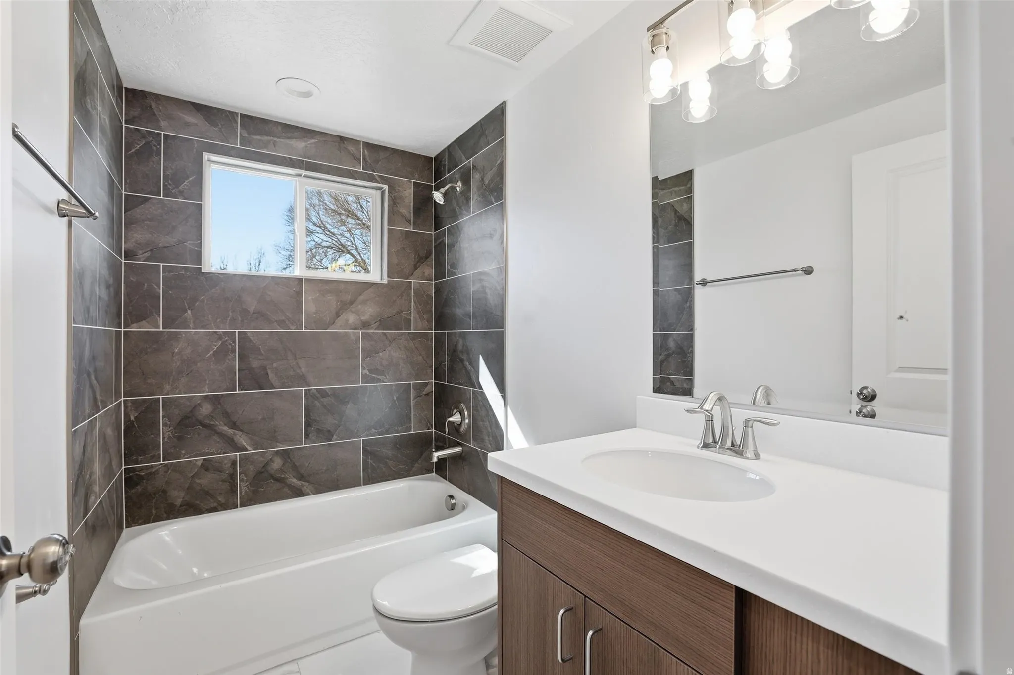 Main Floor Hallway Bathroom featuring vanity and shower / tub combination