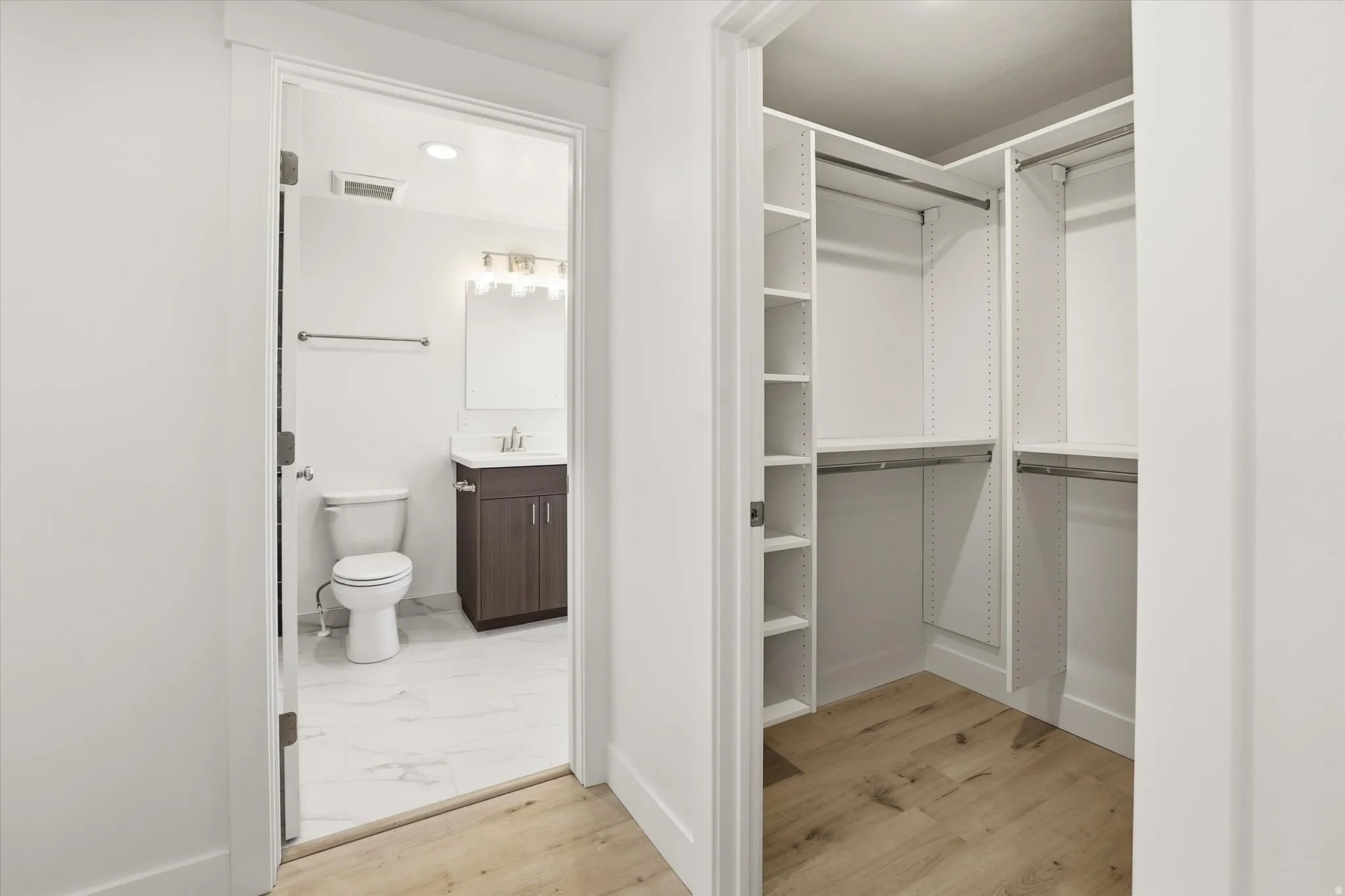 Primary Suite Walk in closet with light wood-style floors and a sink