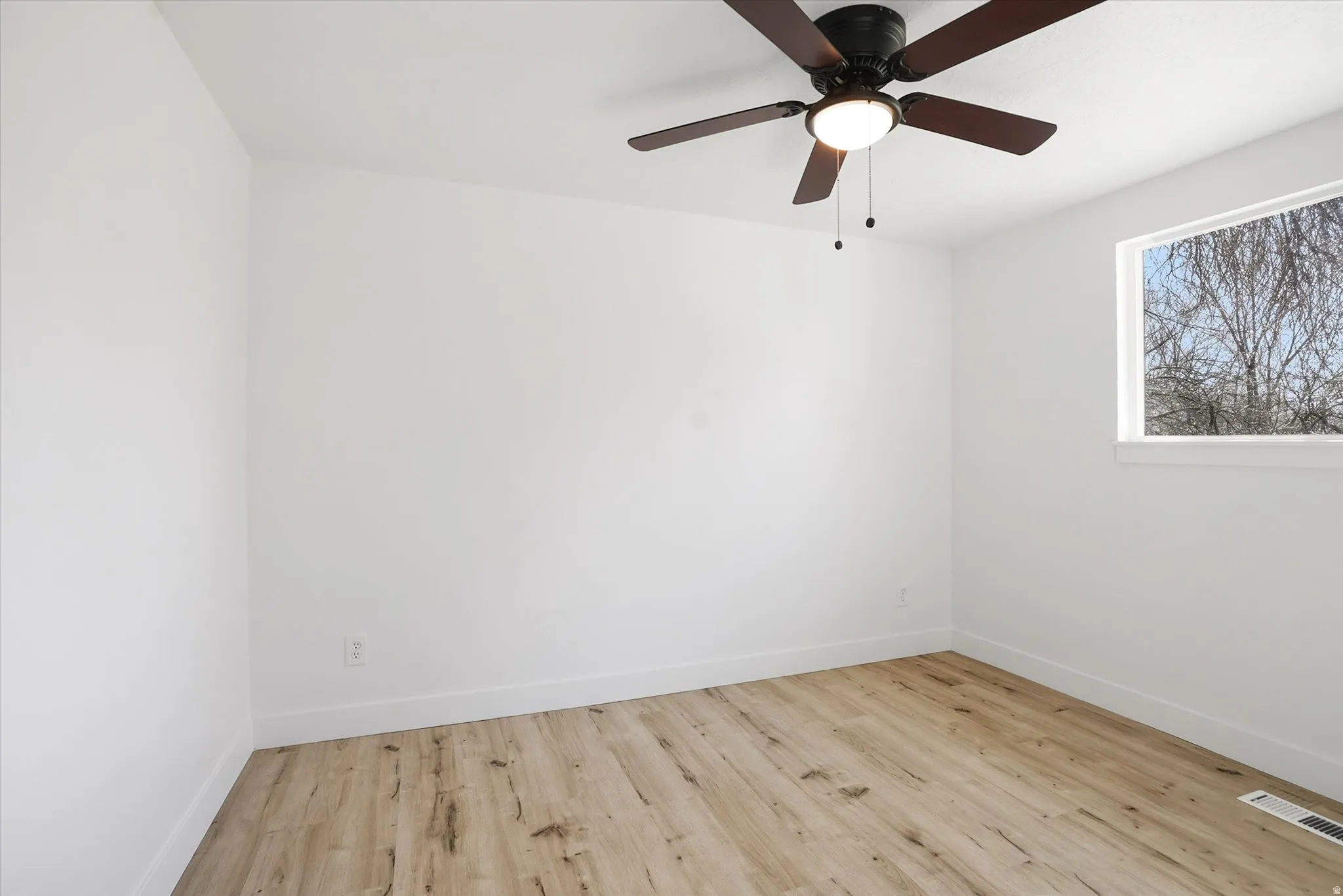Spare room featuring light wood-style flooring and ceiling fan