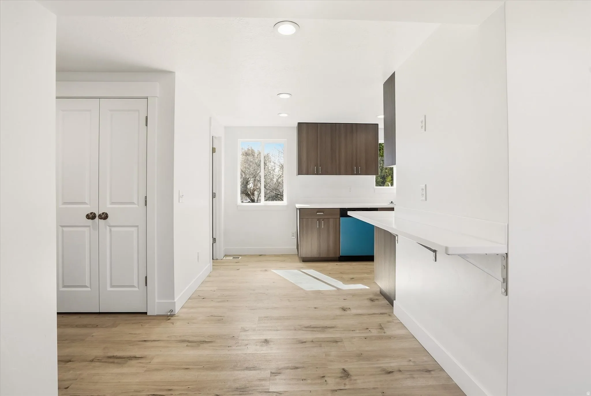 Kitchen featuring dark wood finish cabinetry, light wood-type flooring, dishwasher, a breakfast bar area, and a peninsula