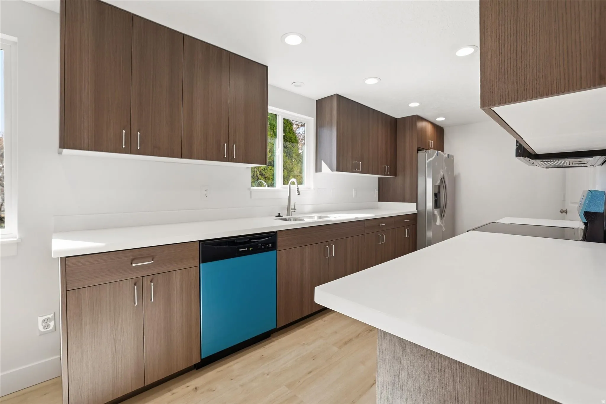 Kitchen featuring light countertops, dishwasher, light wood-style floors, range, and stainless steel fridge with ice dispenser