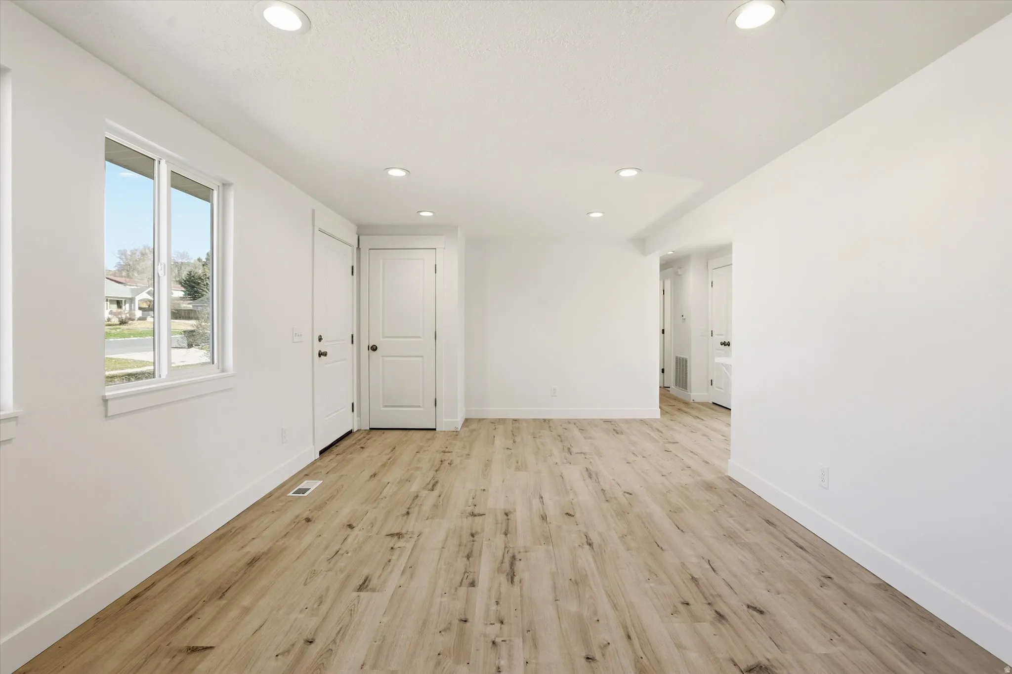 Empty room featuring light wood-type flooring and recessed lighting