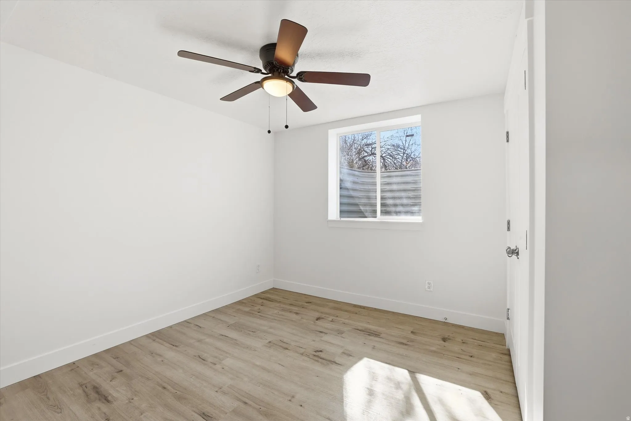 Empty room with light wood finished floors and ceiling fan