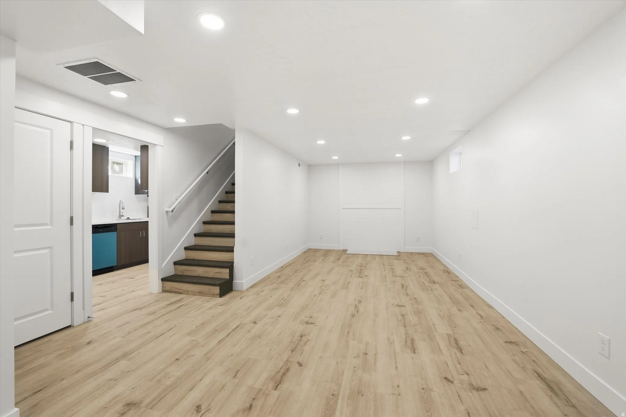 Finished basement with light wood finished floors and recessed lighting